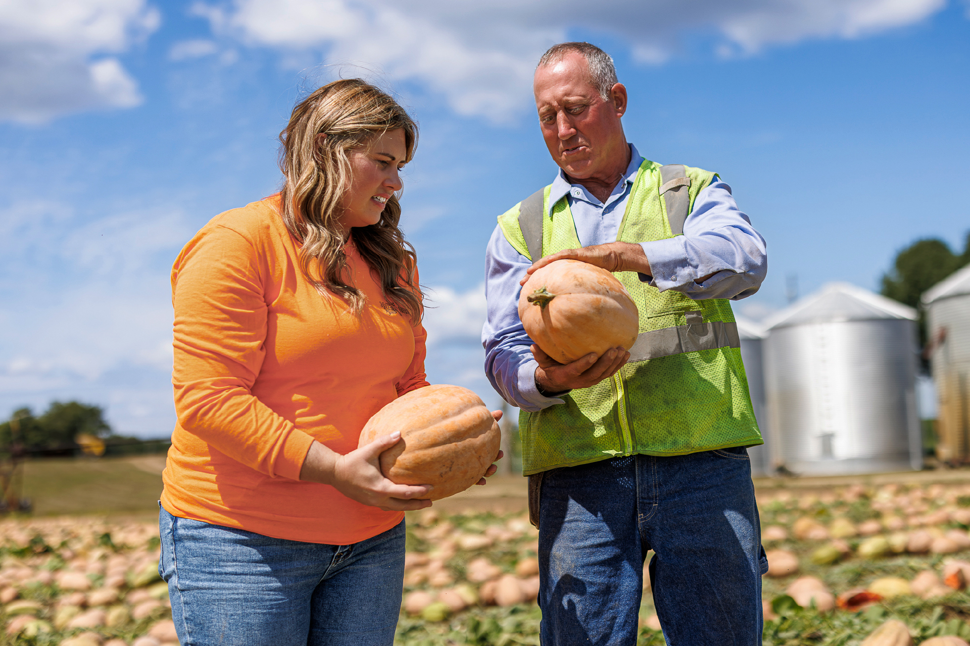Woman and man on farm holding pumpkins