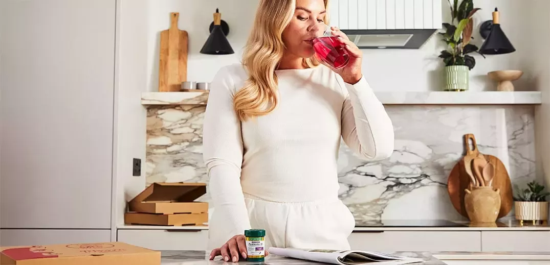 Woman drinking from glass in kitchen