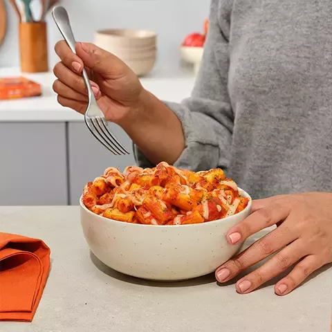 Hand and fork eating Lean Cuisine from bowl