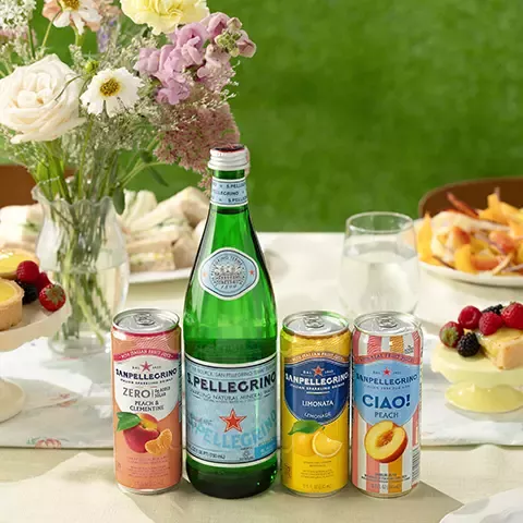 Sanpellegrino drinks lined up on a table with flowers and food